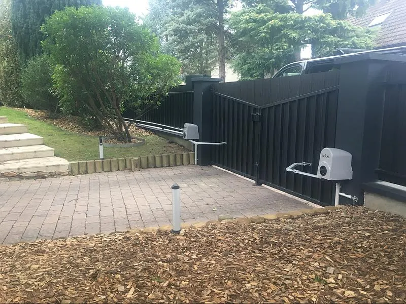 Portail noir motorisé dans un jardin